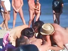 cuatro mujeresdesnudas amigos tienen sexo en la playa nudista frente a multitud